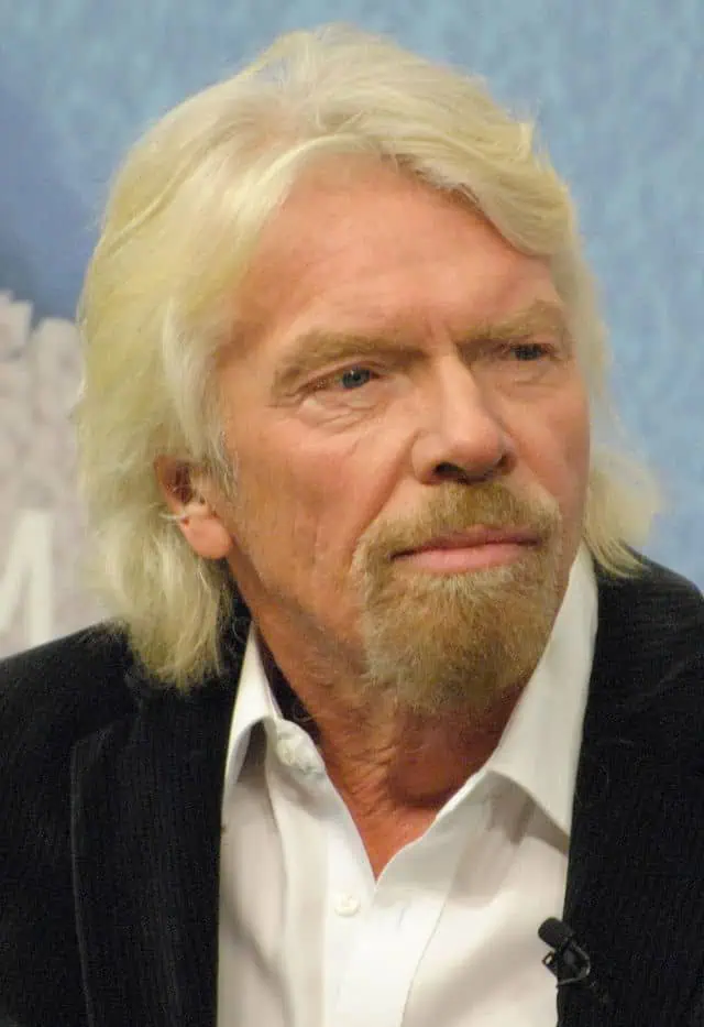 Richard Branson, dressed in a white shirt and dark jacket, gazes thoughtfully, symbolizing his belief that business opportunities are like buses—there’s always another one coming.
